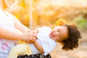 Enfant heureux jouant dans les bras d'une femme