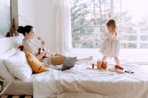 Petite fille jouant et dansant sur le lit de sa maman