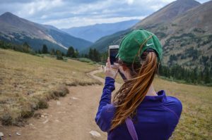 Femme en promenade en montagne prenant photo avec son smartphone