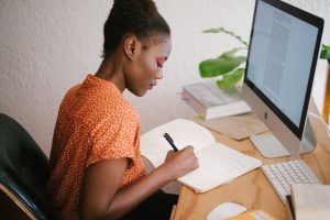 Femme écrivant et travaillant devant son ordinateur