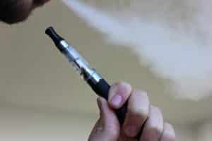 Homme tenant et vapotant une cigarette électronique